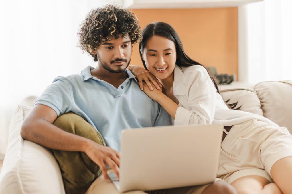 Casal sorridente vendo sites confiáveis pelo notebook