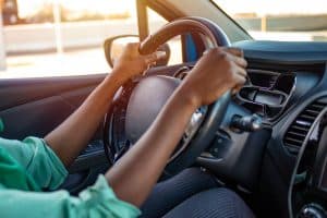 mãos segurando um volante de carro