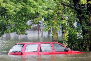 Carro vermelho quase submerso em enchente