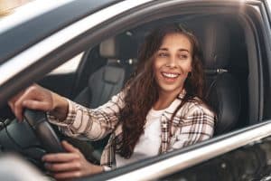 Jovem feliz dentro do seu carro após ter feito seguro auto