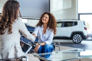 Duas mulheres apertando a mão em uma concessionária de veículos