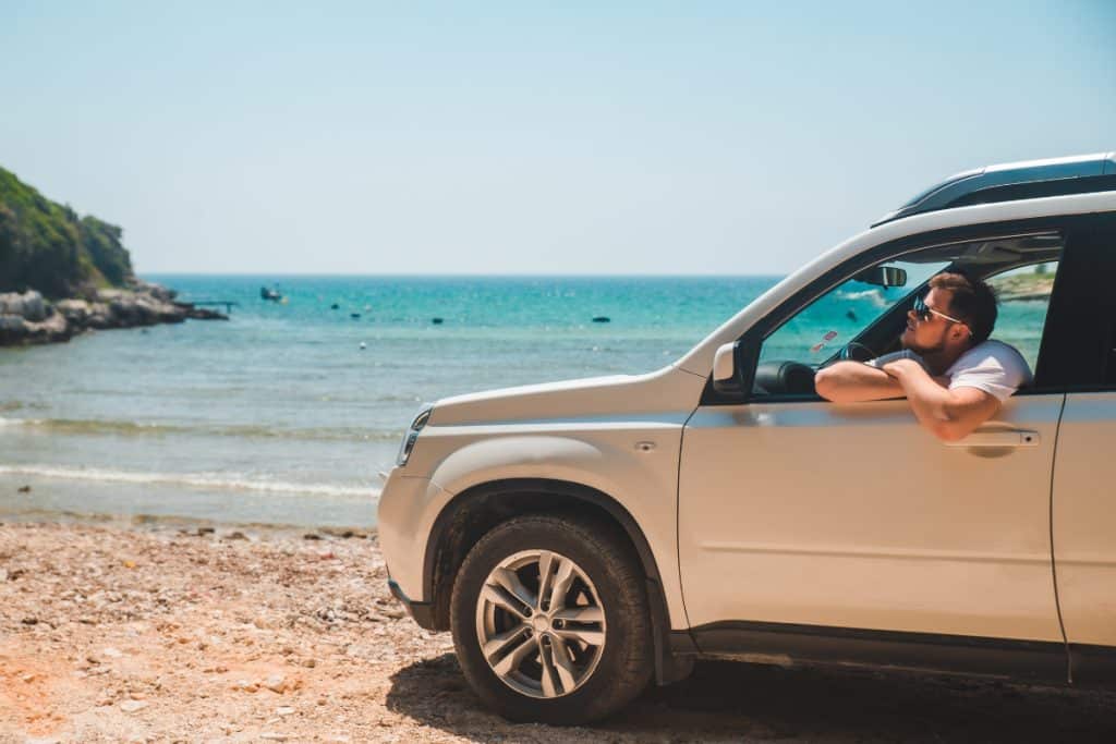 Carro parado frente a praia tomando sol