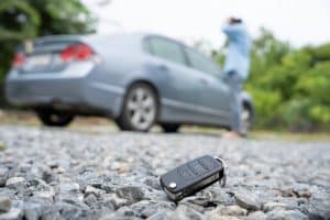 Chave jogava no chão enquanto homem observa o carro