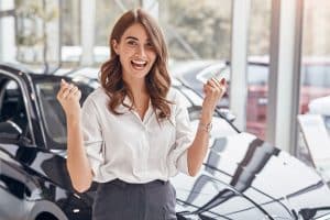 Mulher frente ao carro em concessionária