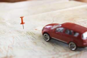 Miniatura de carro sobre um mapa com um local marcado.
