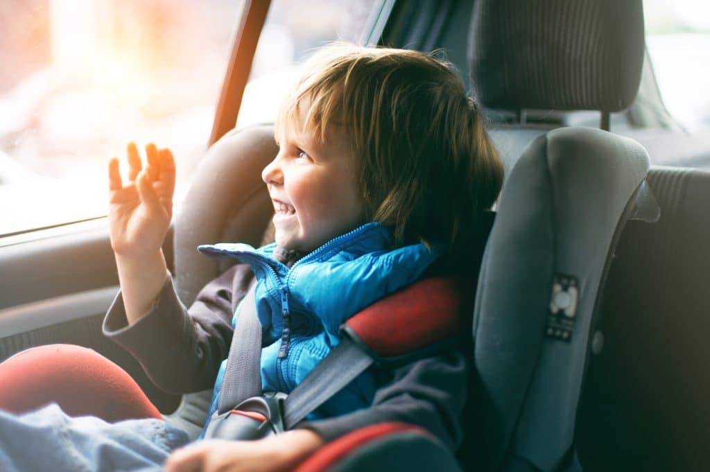 Menino sentado em cadeirinha no banco de trás do carro