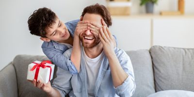 Filho tampando os olhos do pai enquanto entrega presente