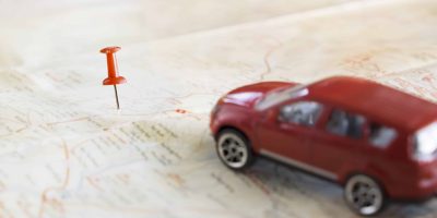 Miniatura de carro sobre um mapa com um local marcado.