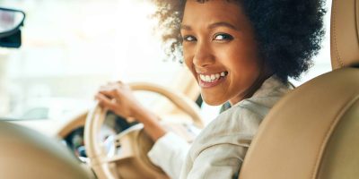 Mulher sorriso em carro após seguro auto para mulheres