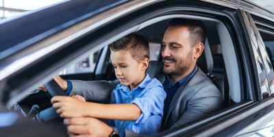 Pai com o filho no colo dentro do carro